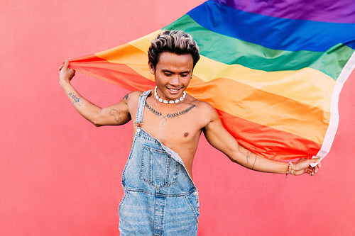 Happy guy with LGBT rainbow flag outdoors