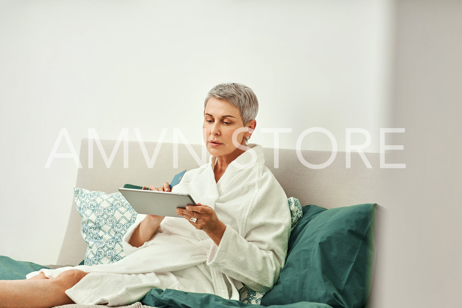 Mature woman relaxing at home. Senior female making online order while lying on a bed.