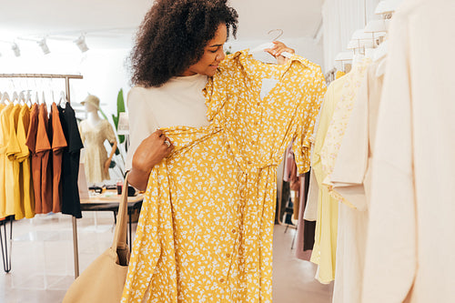 Woman choosing new clothes. Buyer in boutique looking on a dress