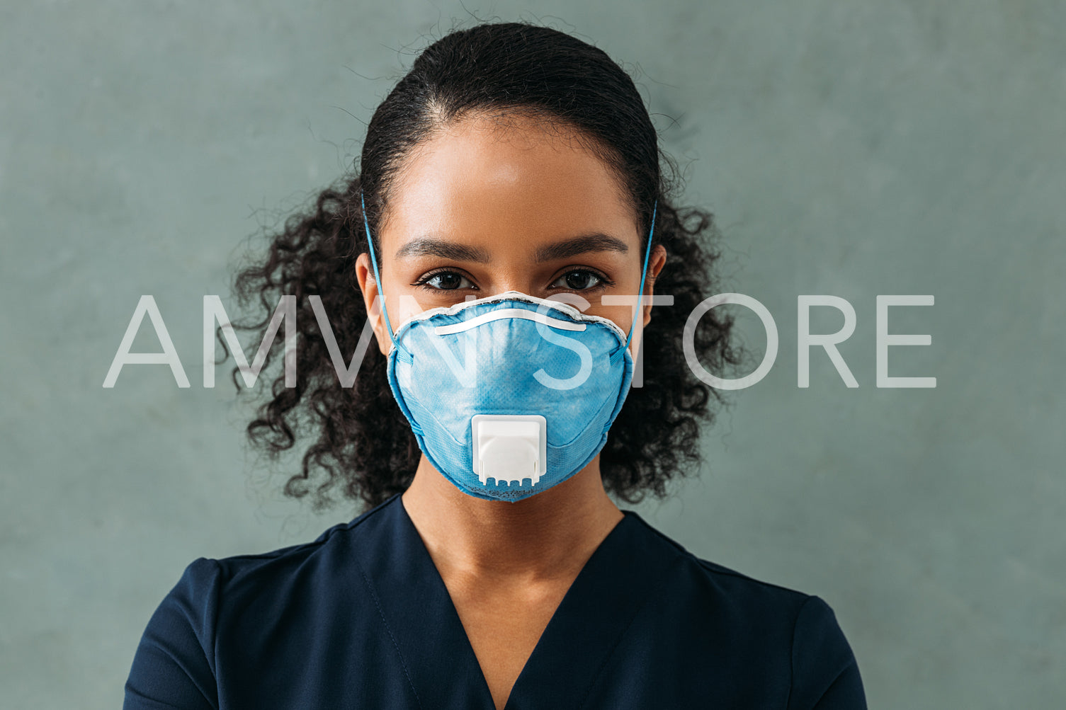 Portrait of a young nurse wearing respirator looking straight of a camera	