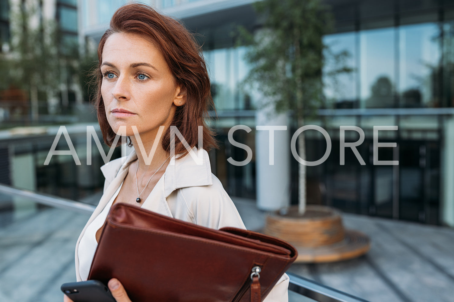 Close-up portrait of a middle-aged businesswoman holding a leather folder against a business building