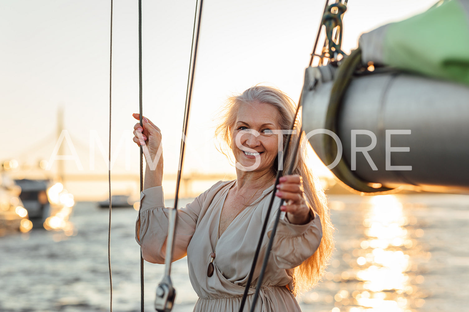 Attractive mature woman posing while standing on a sailboat. Portrait of mature caucasian woman looking at camera outdoors.	