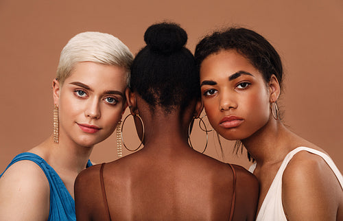 Studio shot of a thee diverse women against brown background