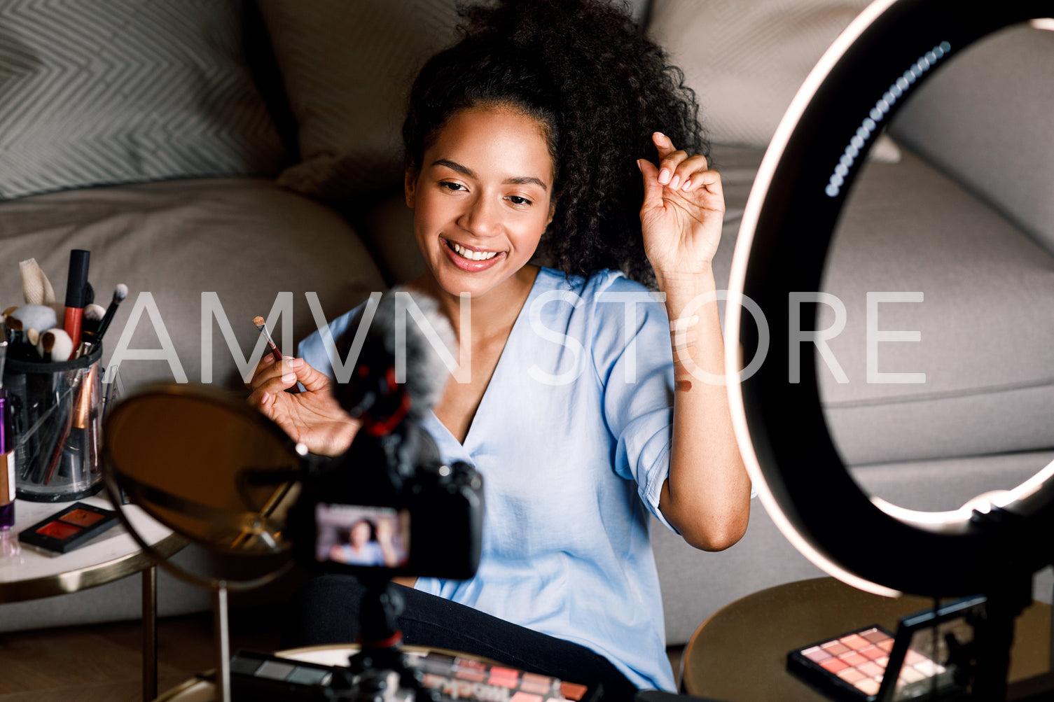 Smiling beauty blogger recording video on DSLR camera from home	