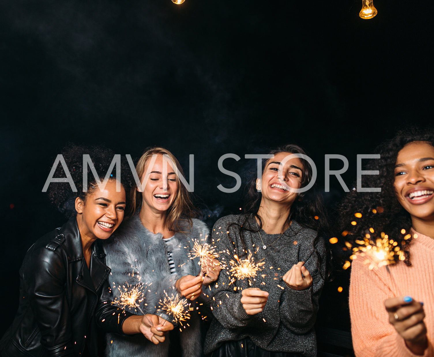 Four happy females with sparklers. Group of diverse female friends celebrating at night.