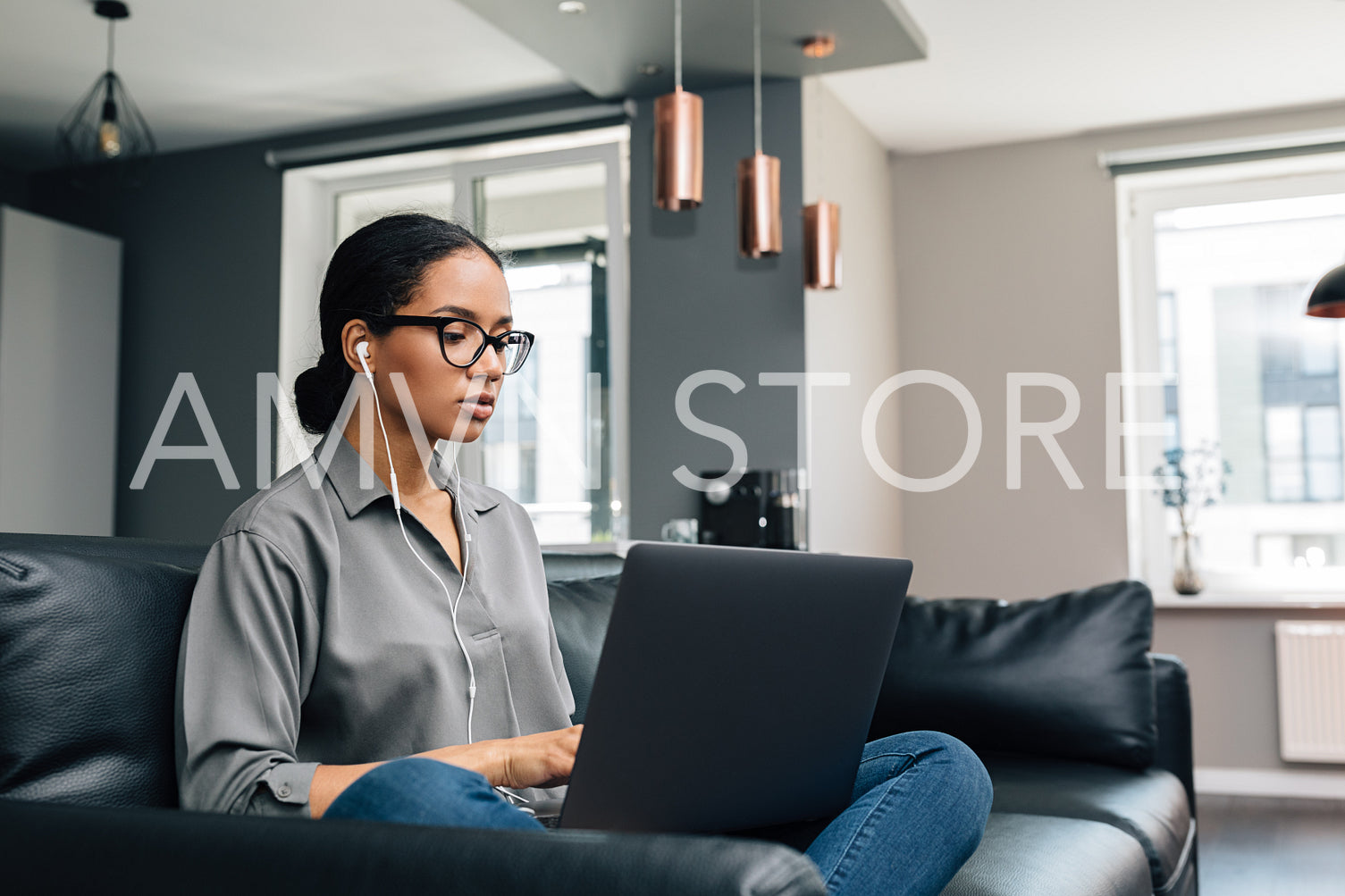 Young woman working from her apartment. Female freelancer using laptop sitting on couch.	