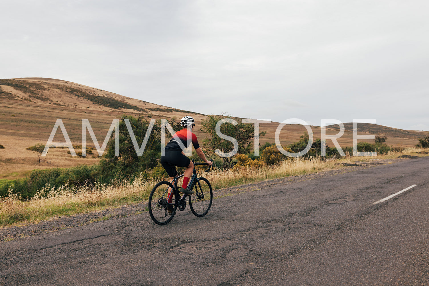 Back view of sportswoman cycling road bike on empty countryside road