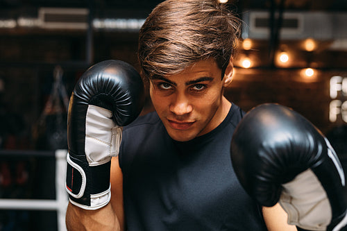 Man boxer in ring wearing boxing gloves, looking at camera