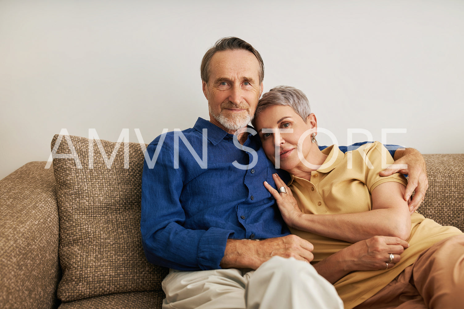 Senior couple embracing on a sofa. Affectionate people hugging at home.	