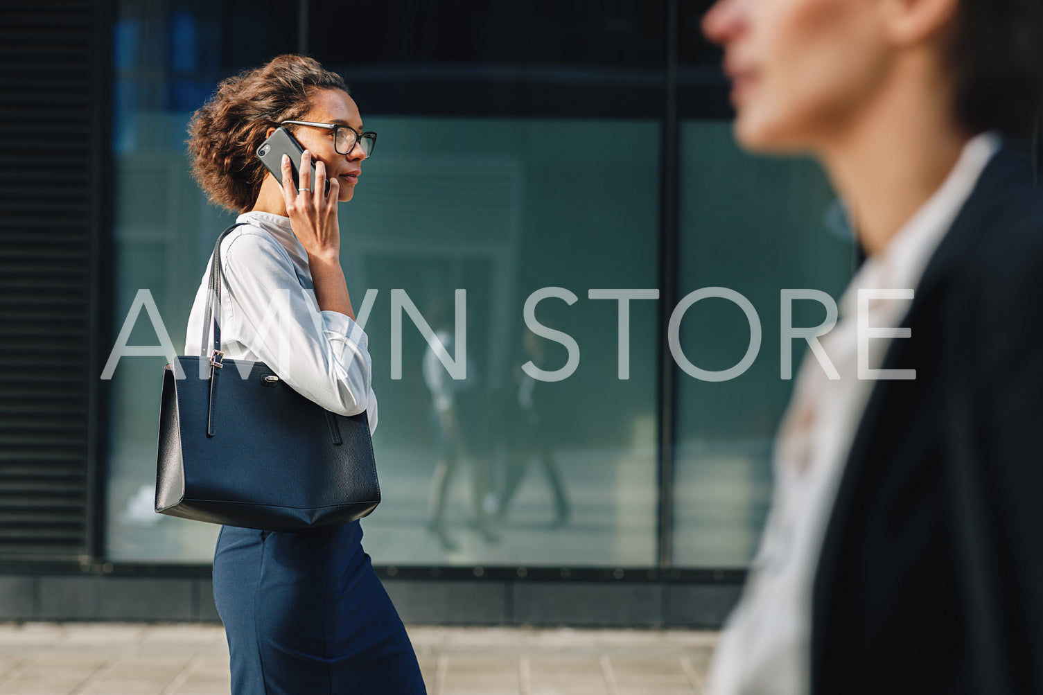 Woman carrying bag walking on city street to the office and making a call	