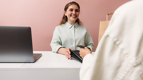 Happy clothing store owner looks at the buyer while he pays with