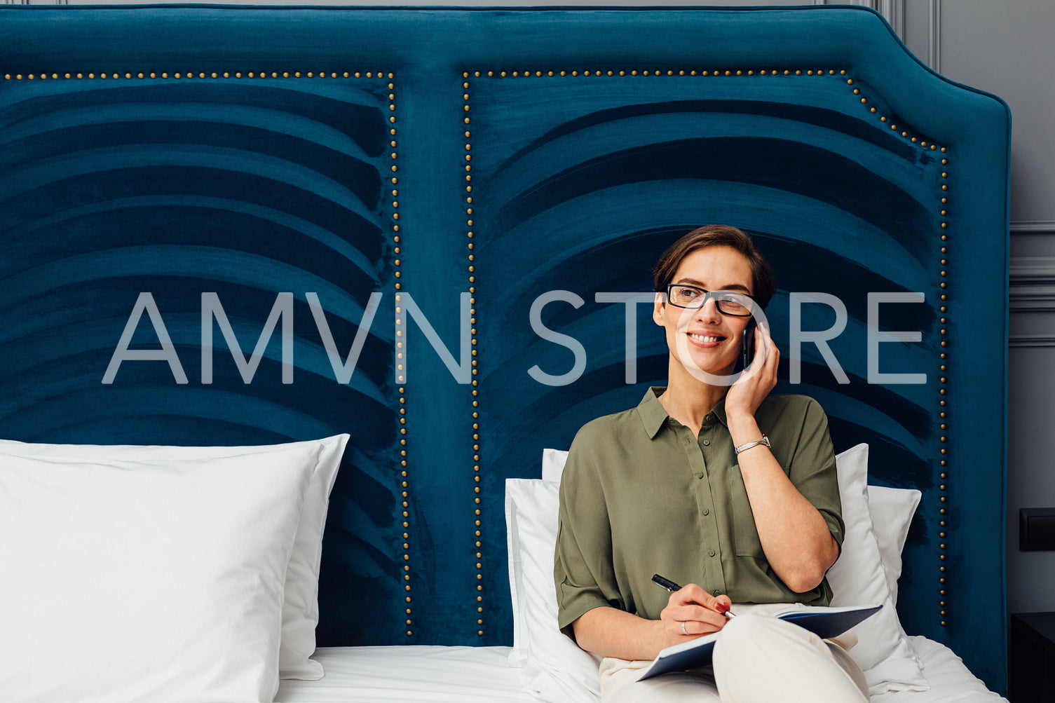 Mid adult woman lying on a bed in hotel room talking on mobile phone and looking away	