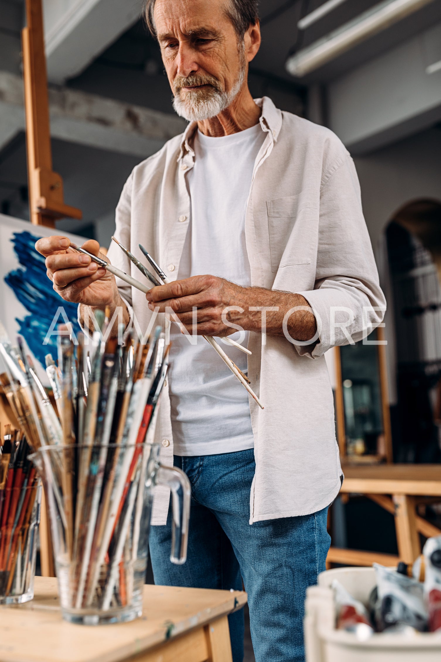 Male artist choosing paintbrushes in his studio	