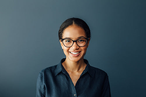 Portrait of a beautiful businesswoman wearing spectacles and looking at camera in living room