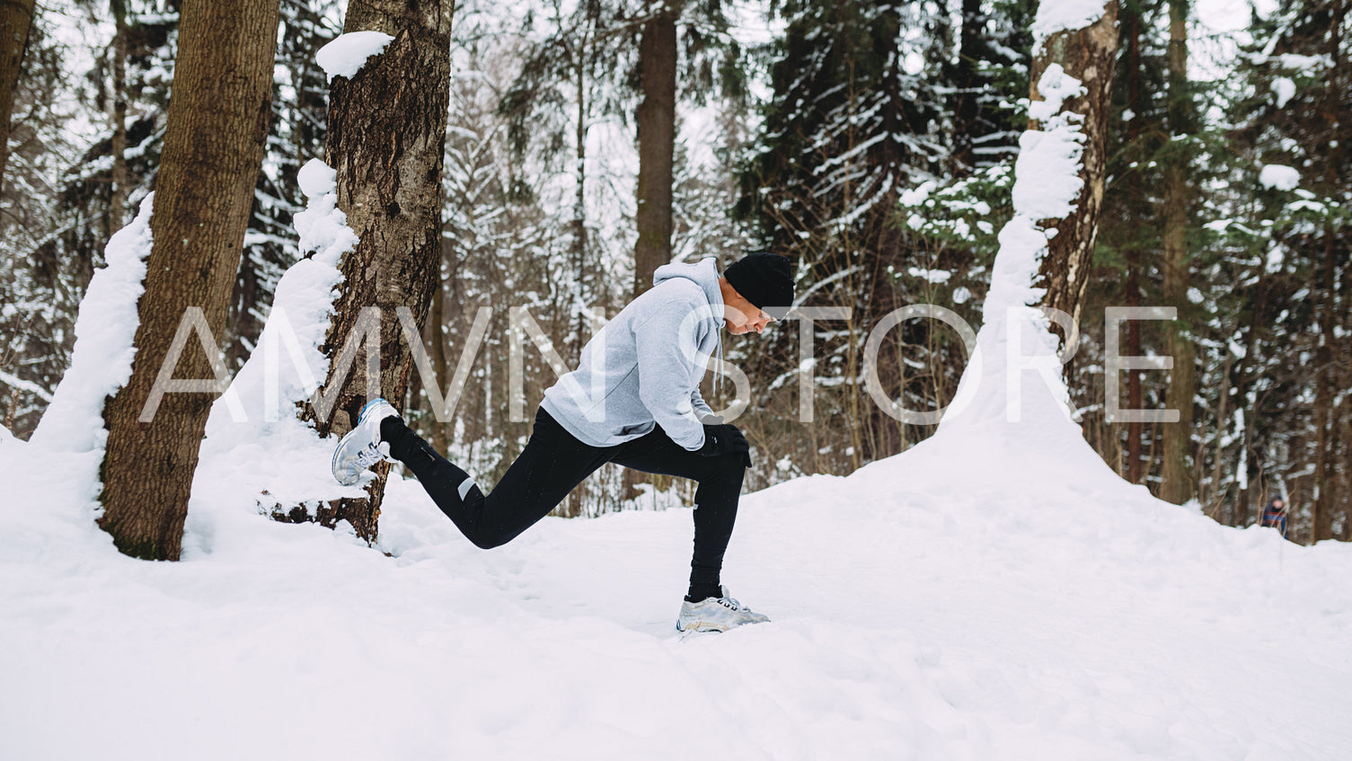 Runner doing stretching exercises in a snow forest	
