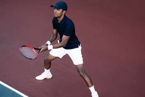 Young tennis player standing on the tennis court baseline ready to return the serve