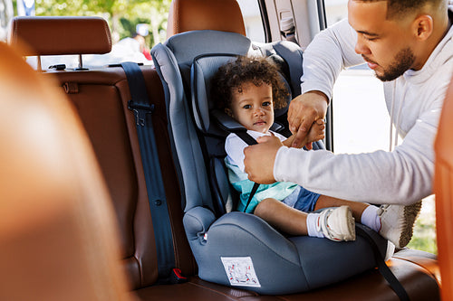 Young father and his little son fastened by belts on the backseat of a car