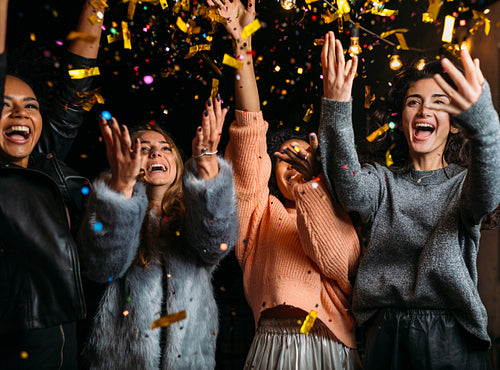 Outdoor shot of happy friends. Happy women throwing confetti at a party.