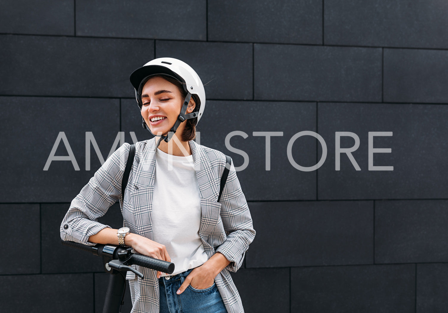 Stylish woman laughing with closed eyes while standing outdoors with electric scooter