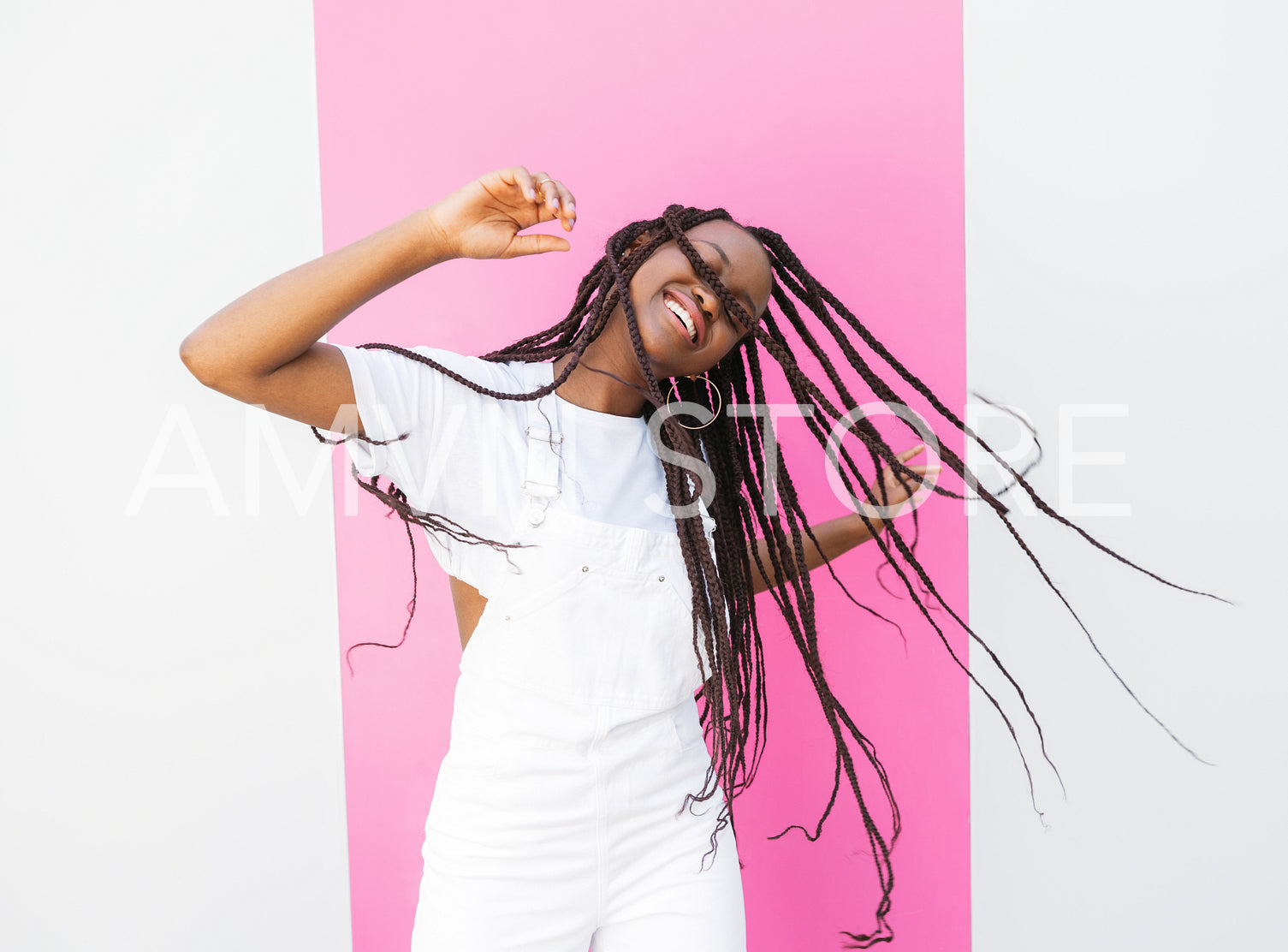 Girl with long braids having fun and dancing at a wall with pink stripe