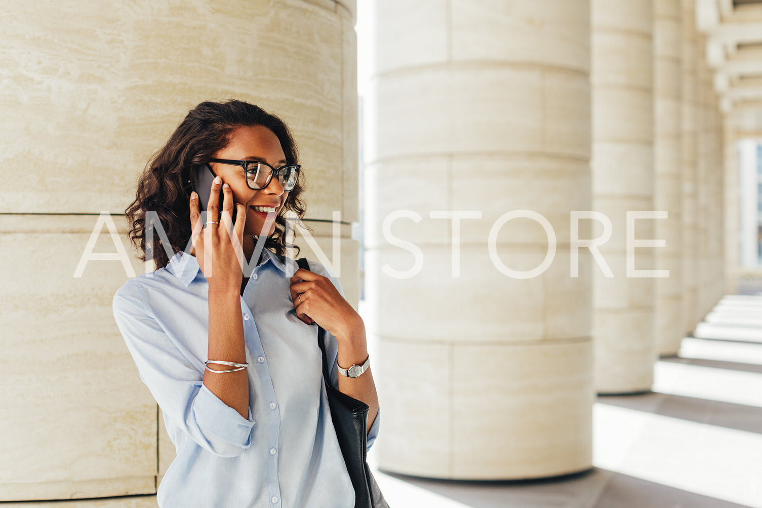 Businesswoman talking on smartphone while standing on city street at office building	