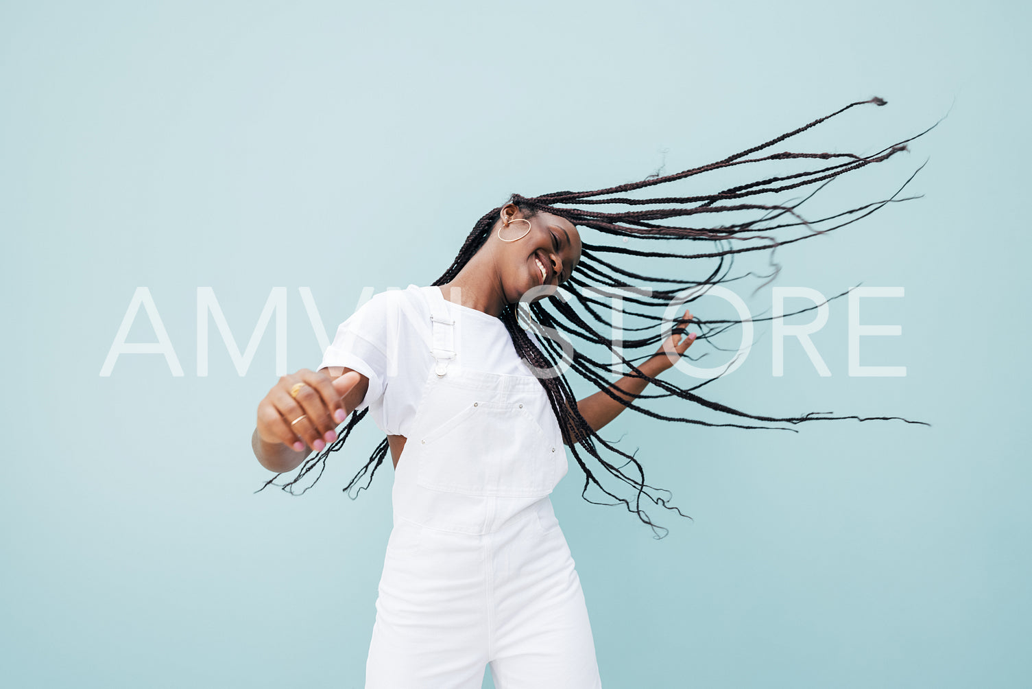 Happy female in white casual clothes flying her long braided hair while dancing