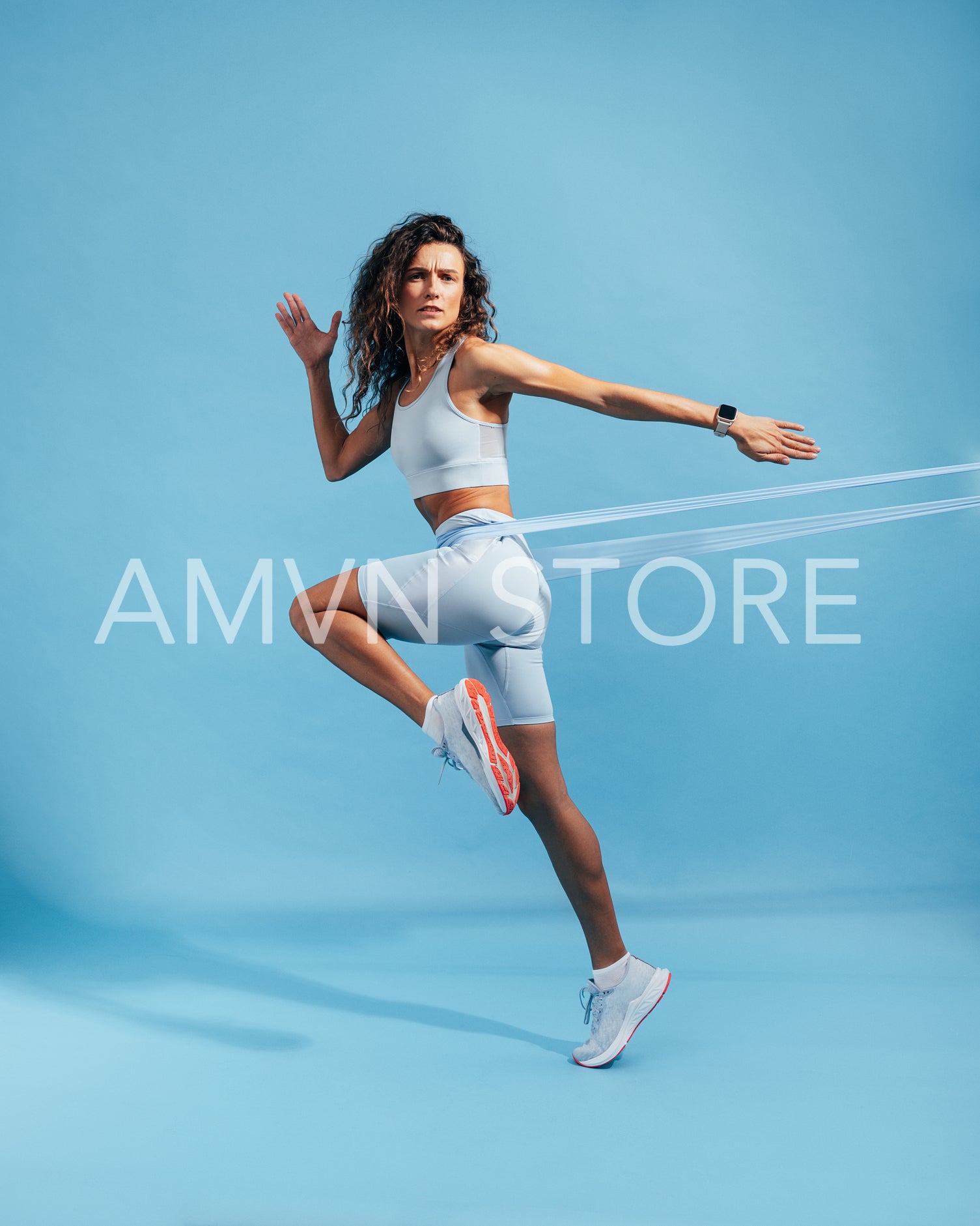 Muscular woman doing intense training with elastic band on blue backdrop