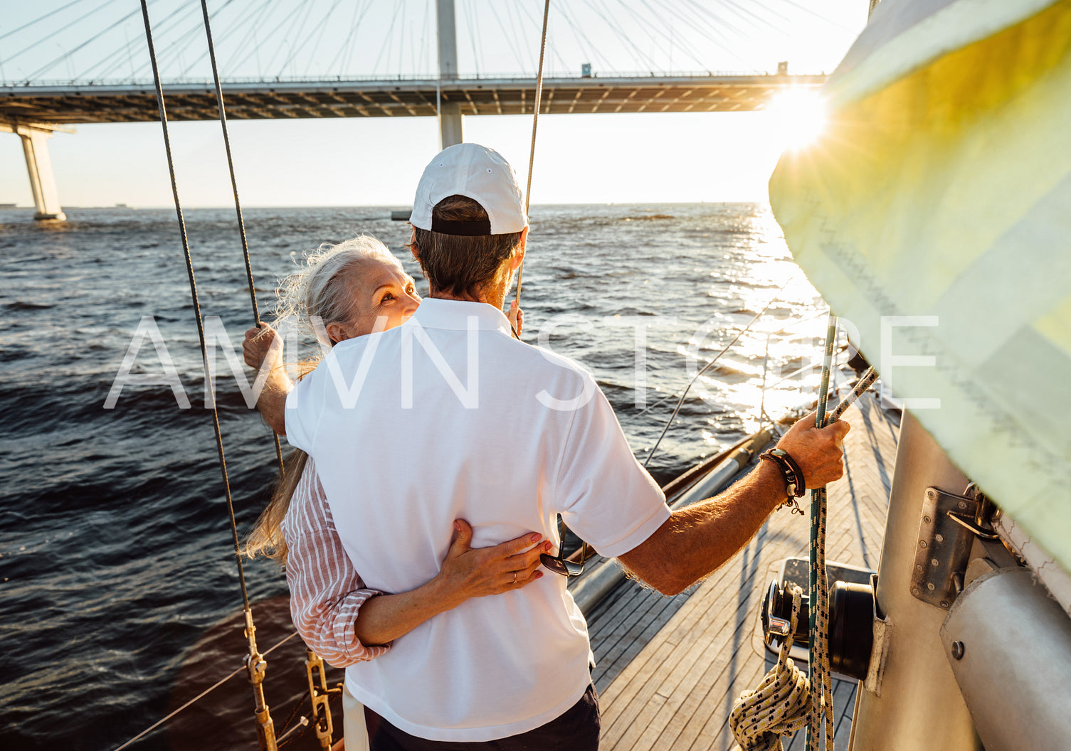 Back view of an elderly couple embracing on a private yacht and looking into distance