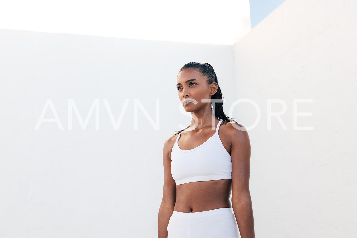 Portrait of a muscular athlete in white fitness attire. Confident sportswoman standing outdoors taking a break.