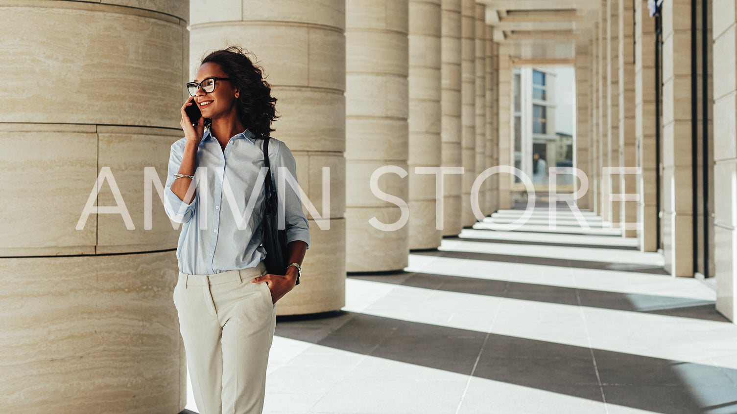 Smiling young african businesswoman walking outdoors and talking on cell phone