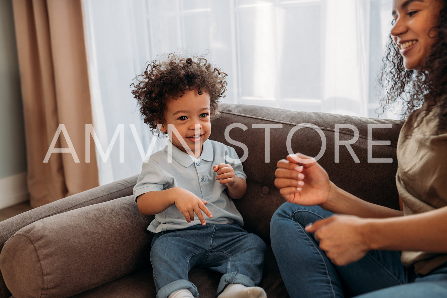 Smiling woman playing with her little son on sofa