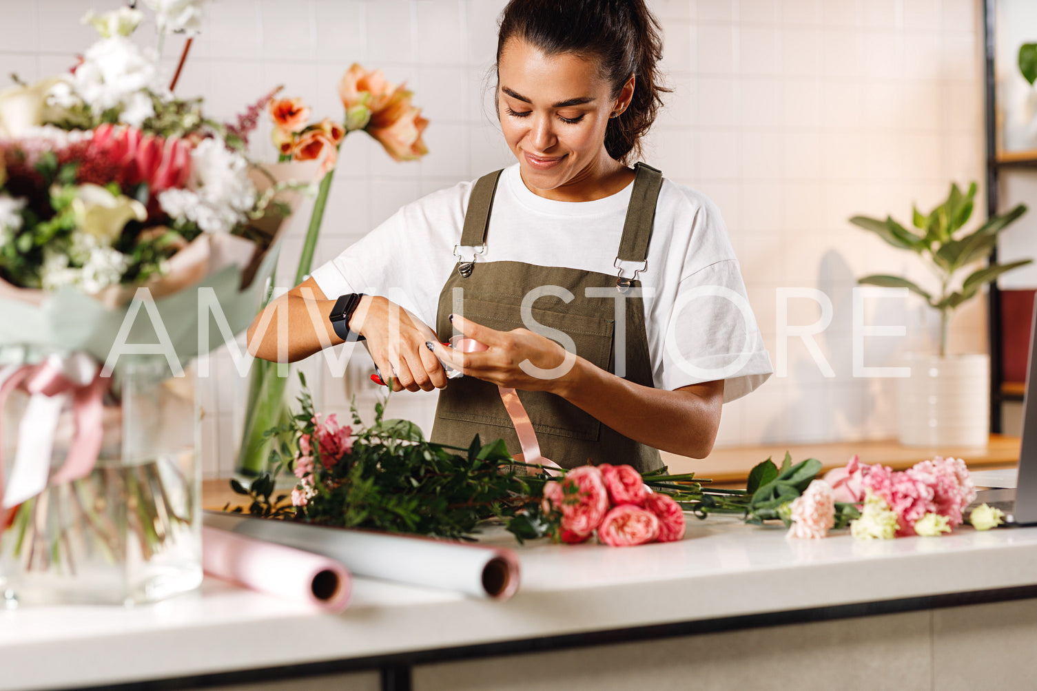 Young woman working in flower shop. Female florist cutting a ribbon for a bouquet.	