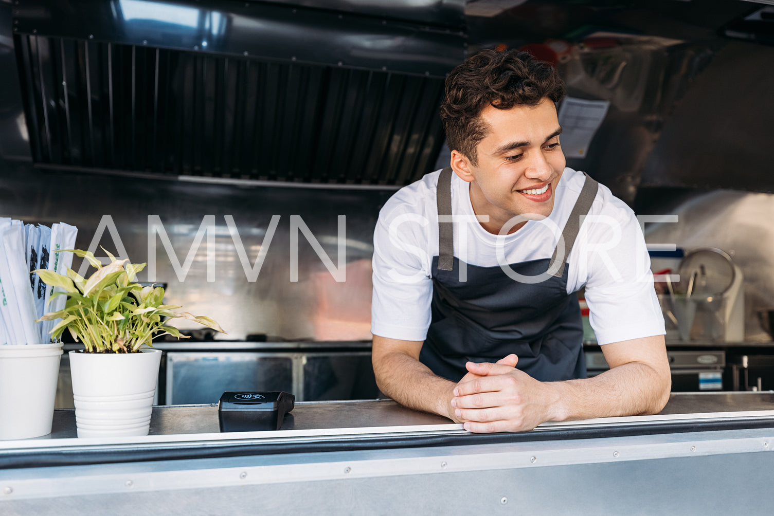 Handsome food truck owner in apron leaning on the counter looking down