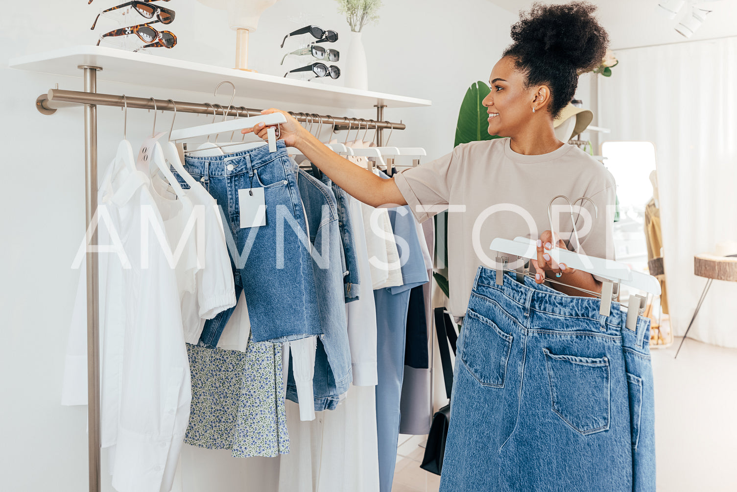 Employee hanging new clothes on a rack. Young woman working in a clothing store.