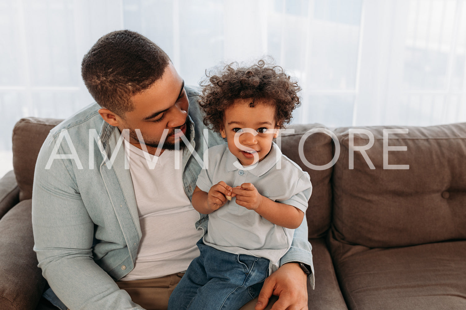 Little boy sitting on father's hip and looking at camera