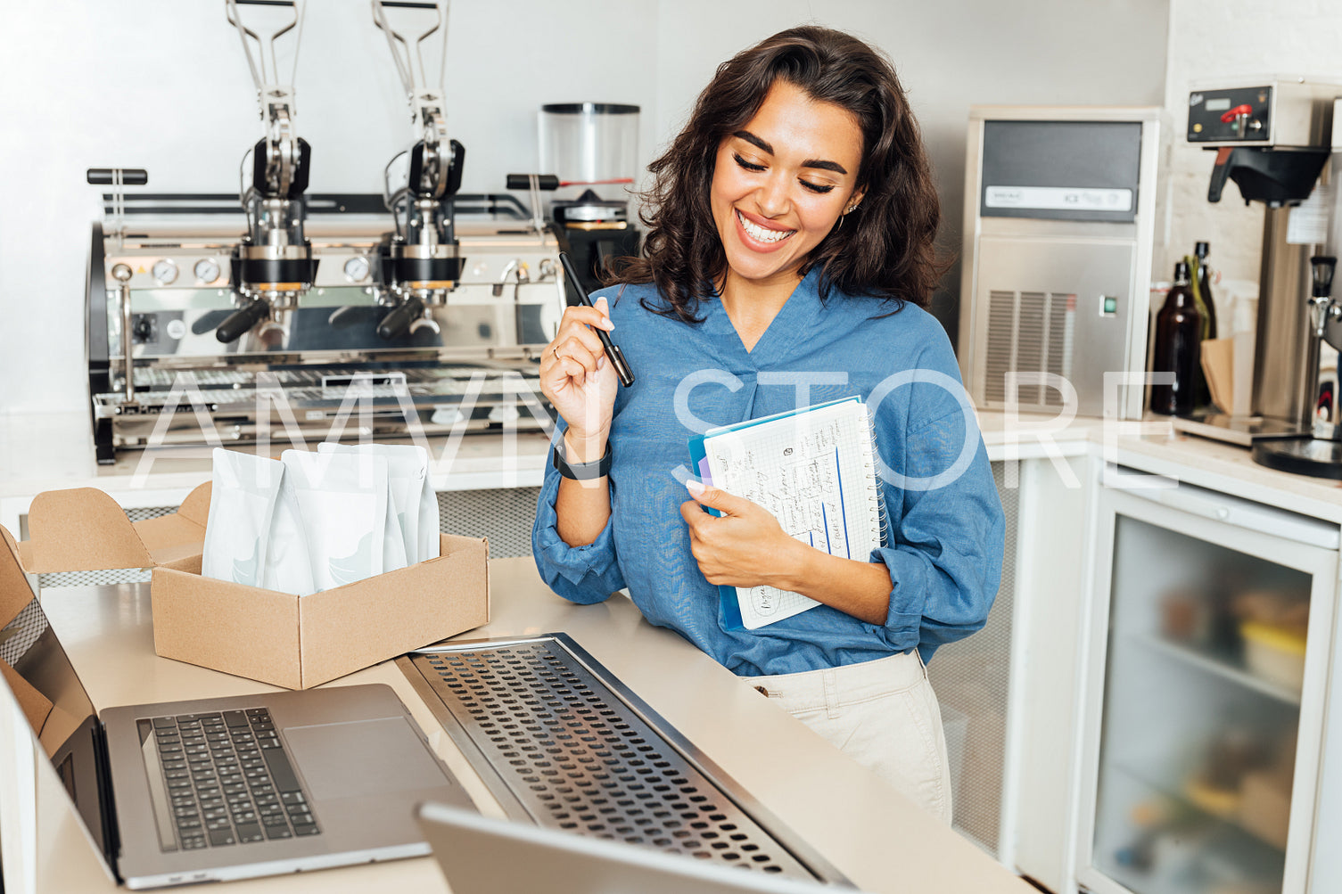 Smiling entrepreneur woman standing at a table in coffee shop. Happy businesswoman in her cafe.	