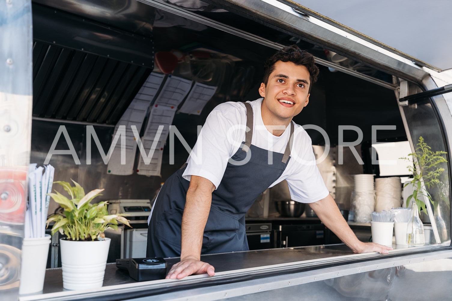 Young food truck owner in apron. Salesman looking away.