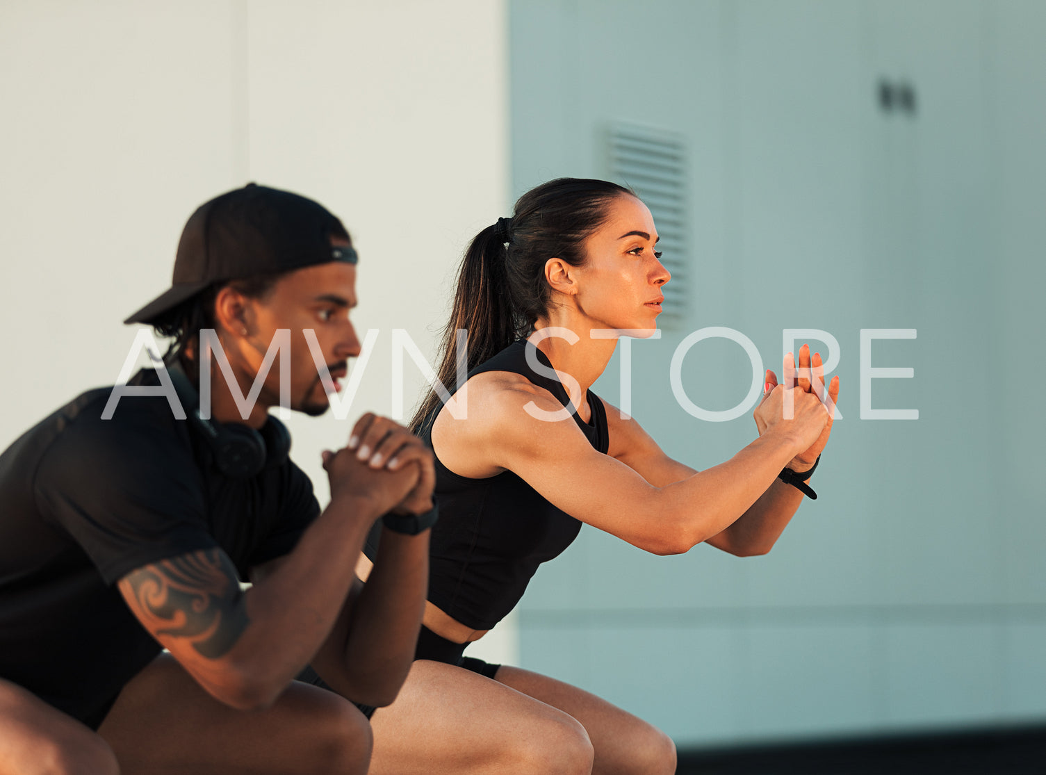 Side view of two athletes doing squats at sunset