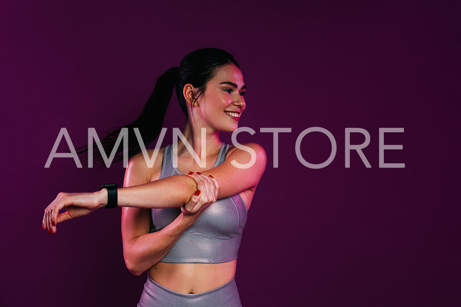 Young positive female flexing her hand while standing a magenta background