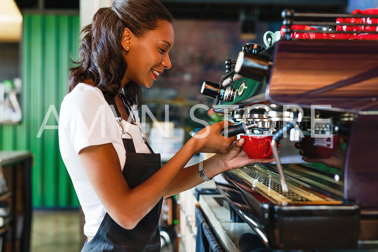 Side view of a smiling female barista making coffee at a cafe	