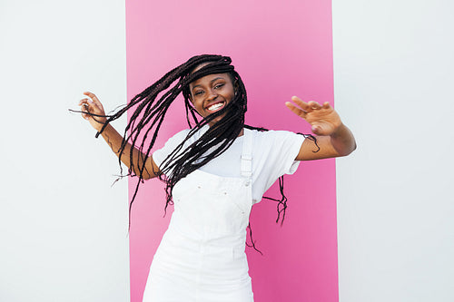 Cheerful girl with long braids enjoying good mood while standing at wall outdoors