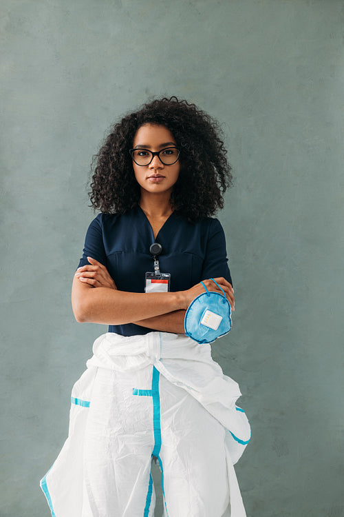 Young medical specialist in eyeglasses holding a mask, wearing a protective suit