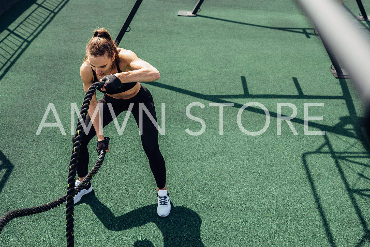 High angle view of fitness woman exercising with two battle ropes on a roof terrace	
