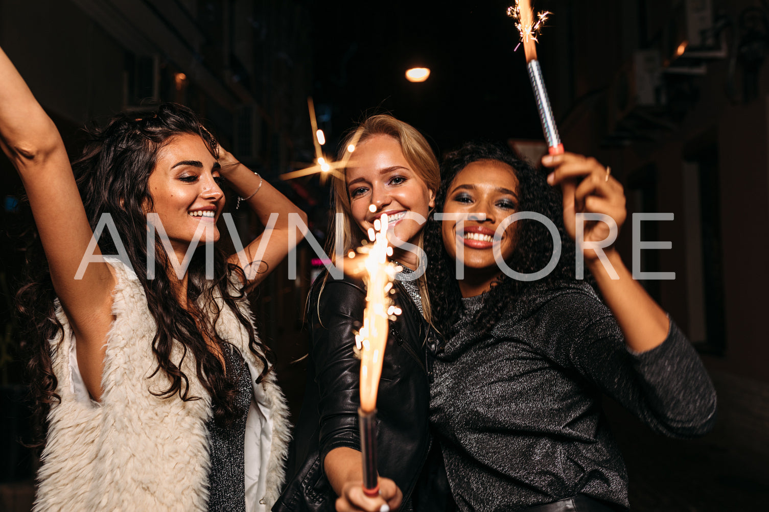 Group of female friends with sparklers enjoying outdoor party at night	