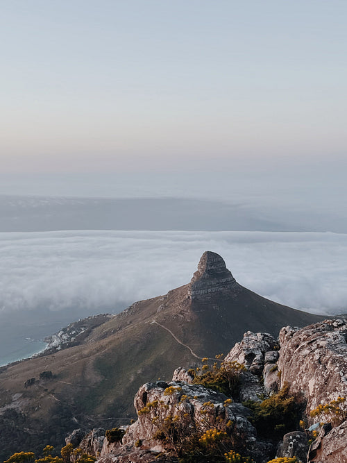 View from above on a big mountain. Clouds cover the city.