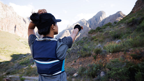 Rear view of sportswoman looking for a path and pointing to the mountain