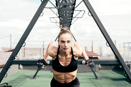 Fitness woman doing triceps dip using power rack on a terrace