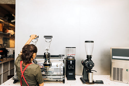 Rear view of barista using coffee maker in coffee shop