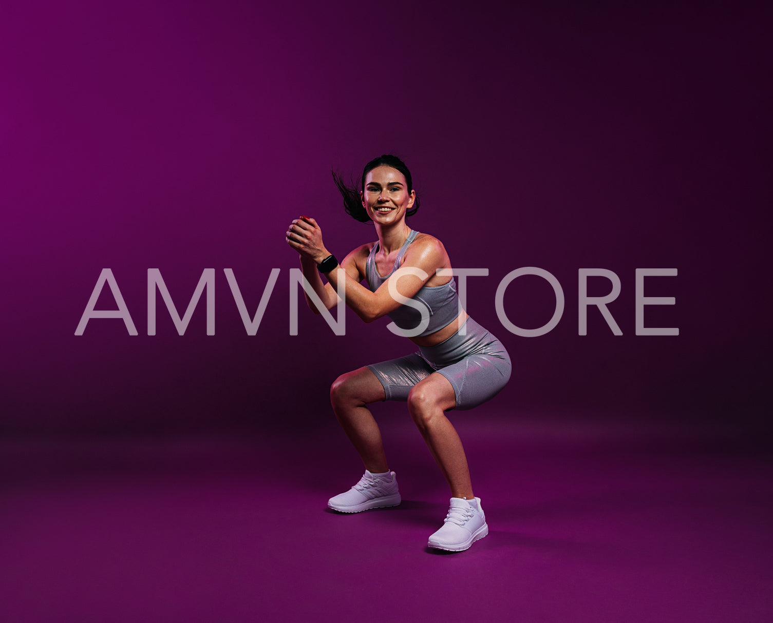 Young smiling woman in silver fitness attire doing sit-ups on a magenta background