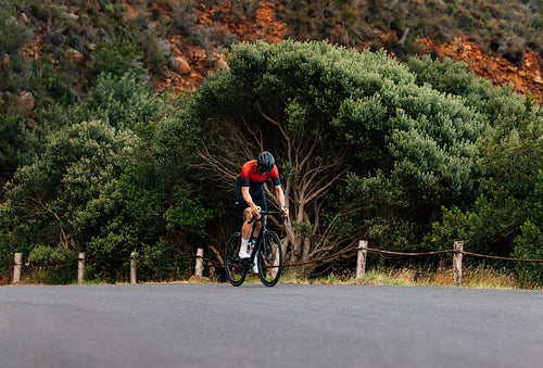 Young man riding a bicycle in wild terrain. Road bike rider practicing outdoors.